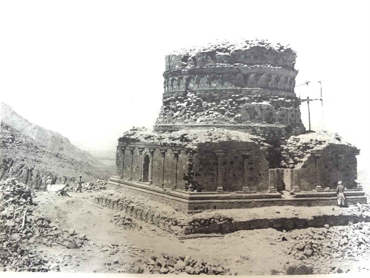 A black and white photo of an ancient building in Afghanistan in a rocky terrain. The building looks to be made of stone and is crumbling.