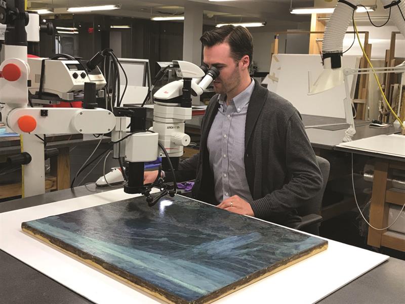 Jeff Richmond-Moll looking at a painting under a microscope