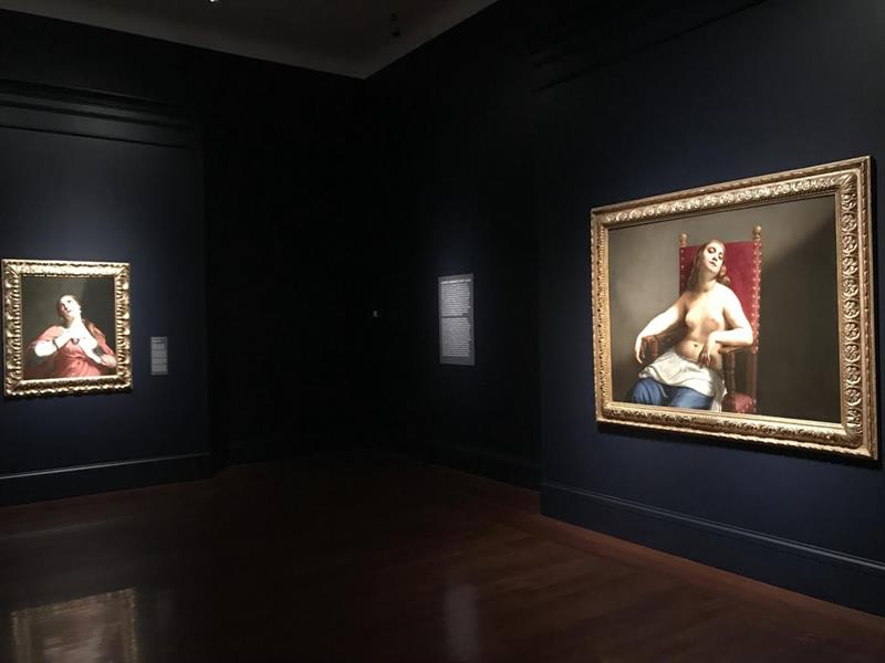 an exhibition view featuring two large baroque paintings in a gallery room. 