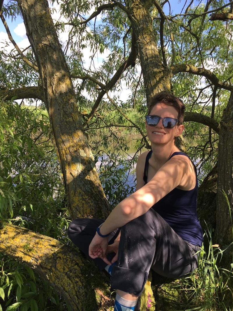 Sarah Leonard sitting in a tree wearing sunglasses