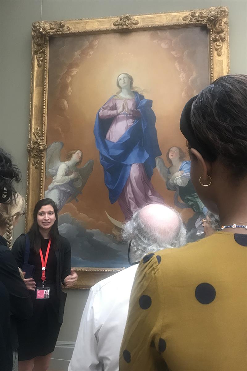 Hein speaks to a small crowd of museum guests in front of her and Guido Reni's The Immaculate Conception.