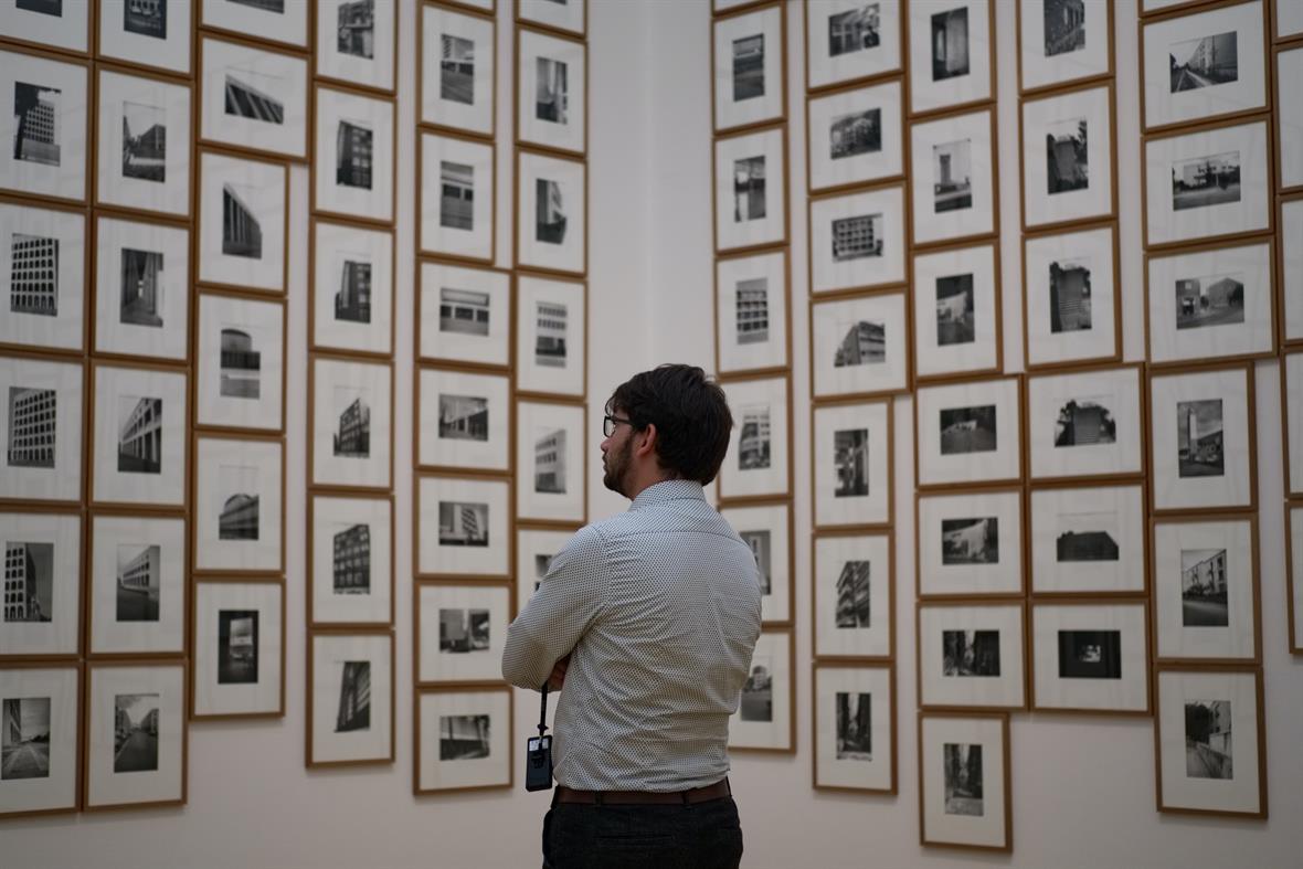 A man looks at photographs in a gallery.