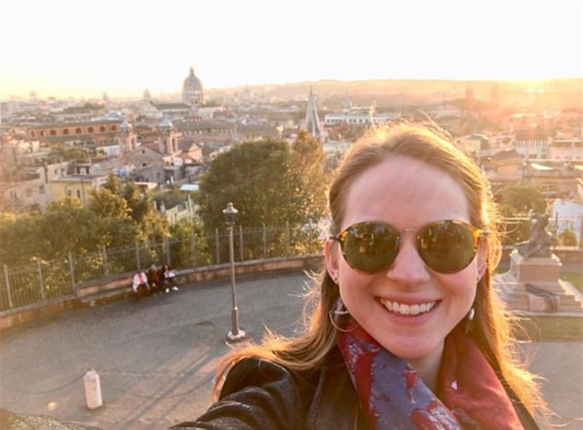 Emily Shartrand smiles with Rome skyline behind her.