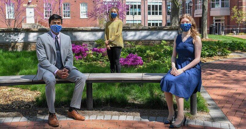 Nishant Chintala and Miriam-Helene Rudd sit on a bench and Jessica Harding stands behind them.