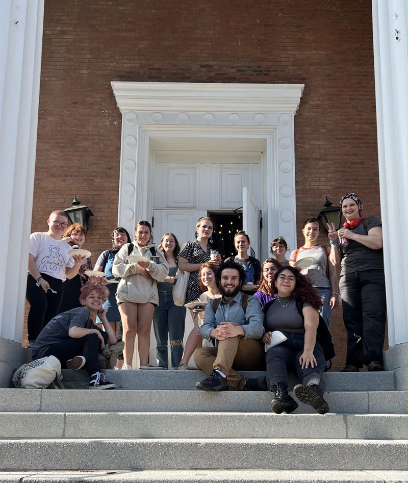 a group of students sitting and standing on the steps of a brick building